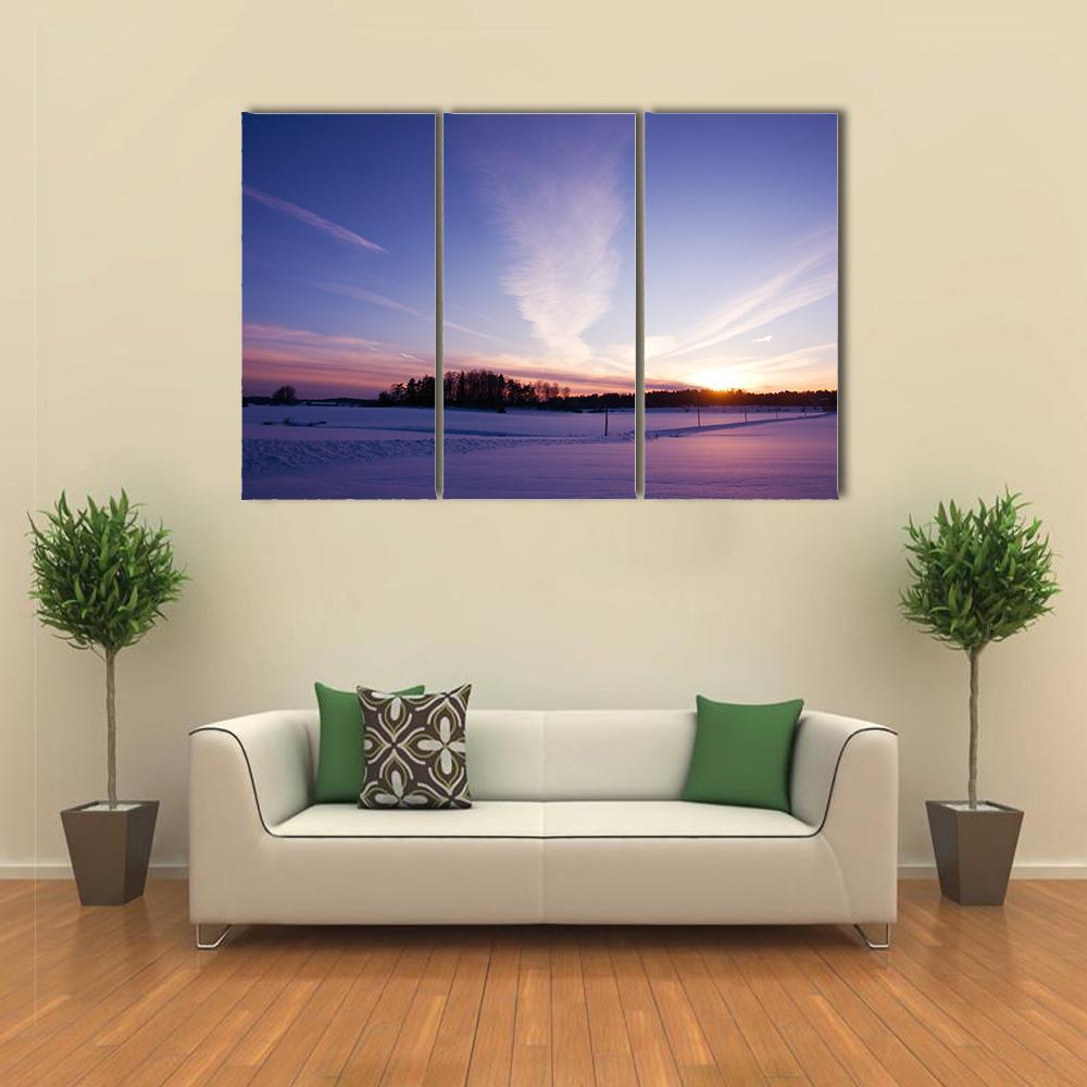 Winter Sunset Over Snowy Field Canvas Wall Art in white, blue and purple, 3 panel horizontal set hung on a wall