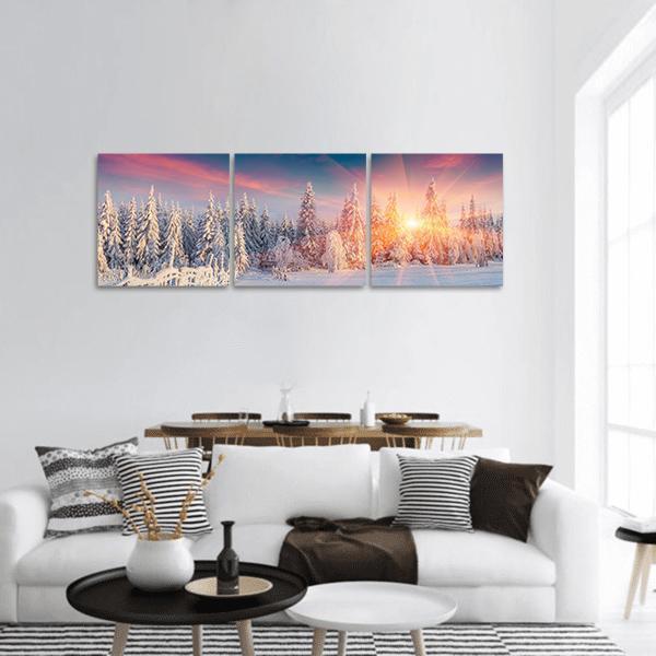 Winter Sunburst Over Snow-covered Evergreens Panoramic Canvas Wall Art in white, orange and blue, hung on a wall