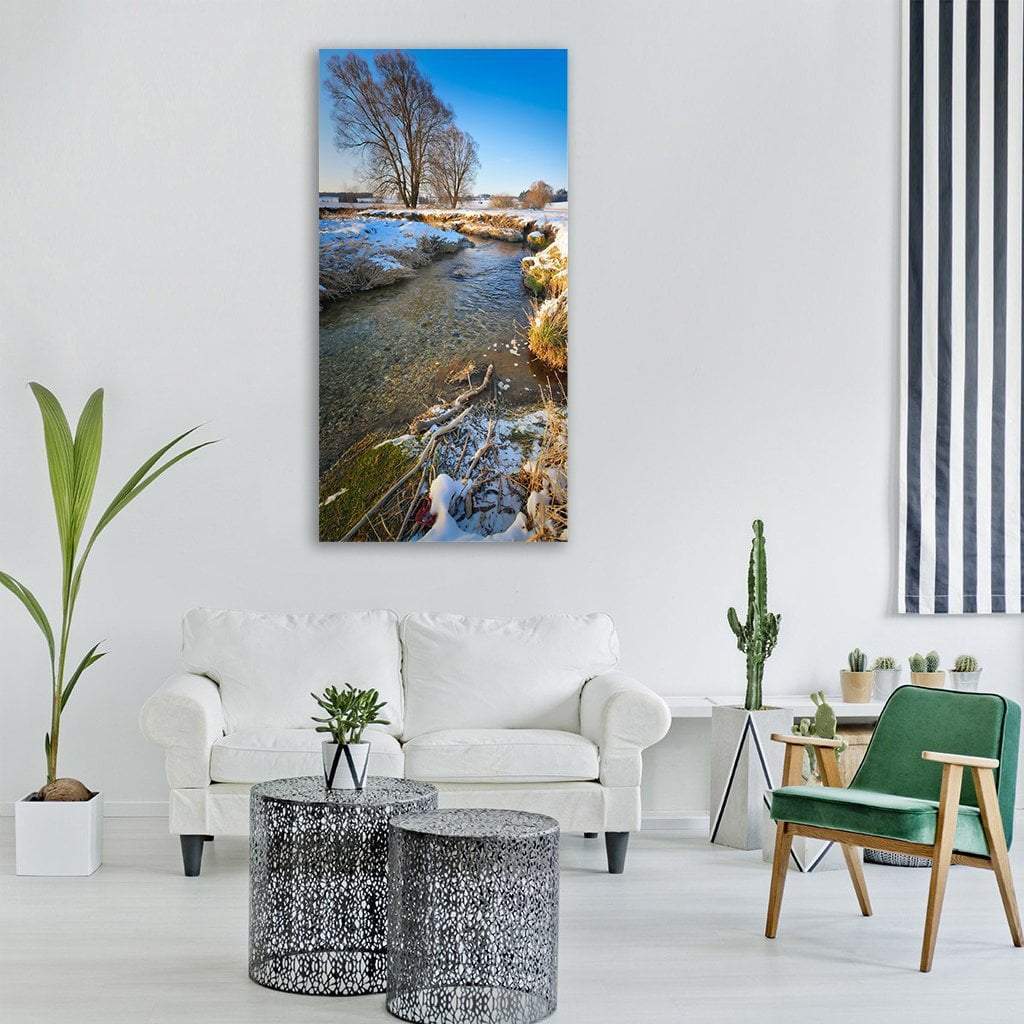 Winter Stream with Frosted Foliage Vertical Canvas Wall Art in white, brown and blue, single vertical panel hung on a wall