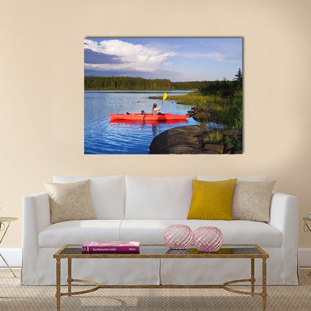 Canoeing at Sunset on Serene Lake Canvas Wall Art in orange, green and blue, single panel hung on a wall
