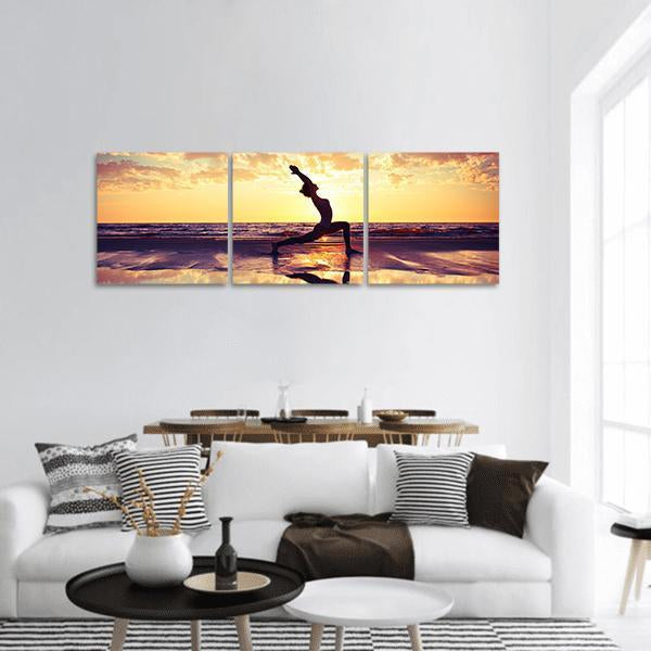 Woman in Crescent Lunge on Beach at Sunset Panoramic Canvas Wall Art in orange, yellow and blue, single panel hung on a wall