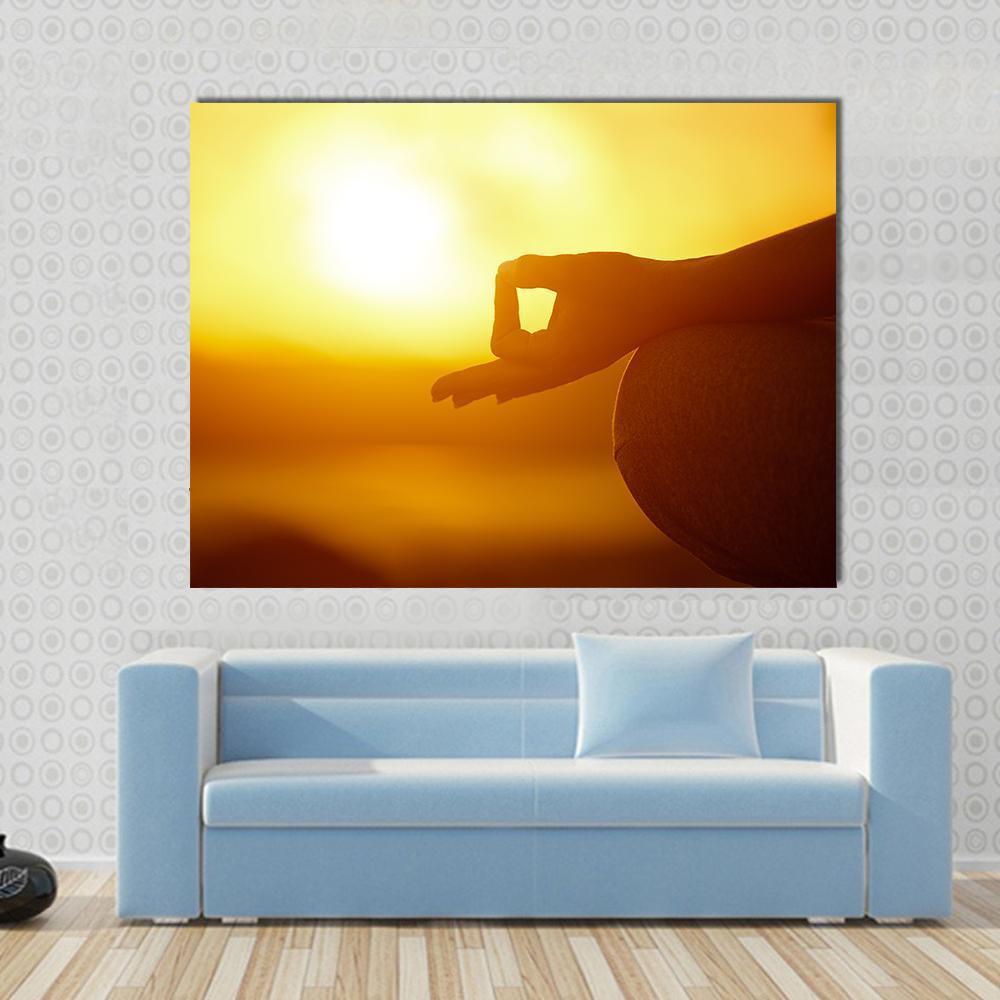 Woman Practicing Yoga Lotus Pose on the Beach Canvas Wall Art in orange and yellow, single panel hung on a wall