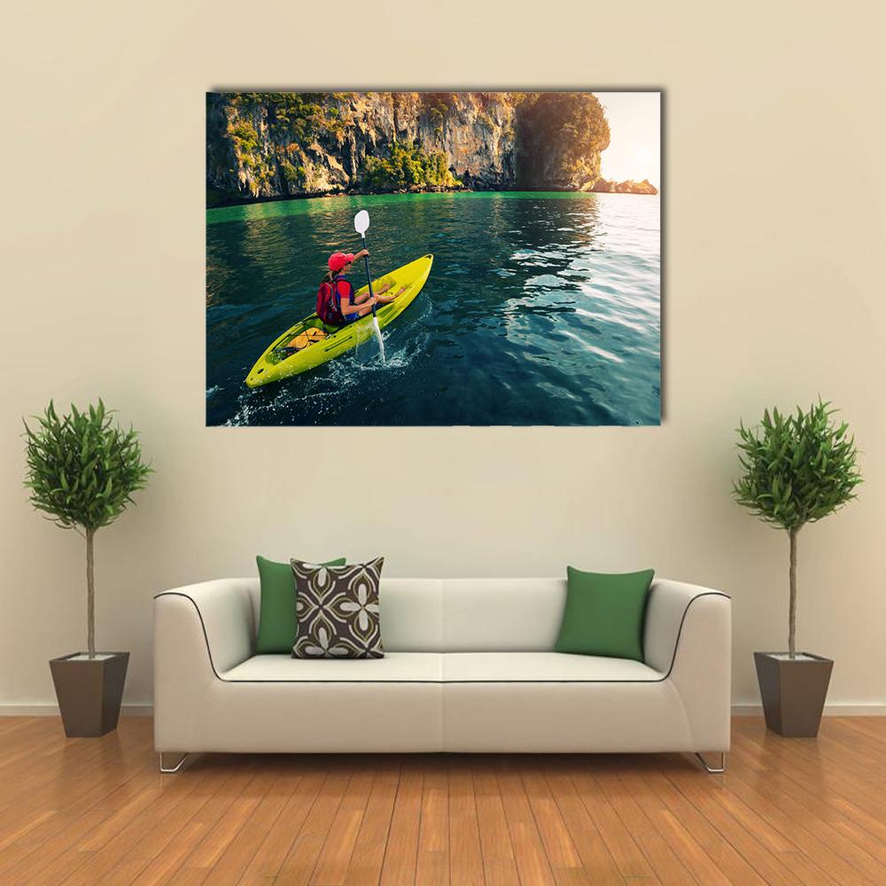 Kayaker in Yellow Boat by Turquoise Cliffs Canvas Wall Art in yellow, green and blue, single panel hung on a wall