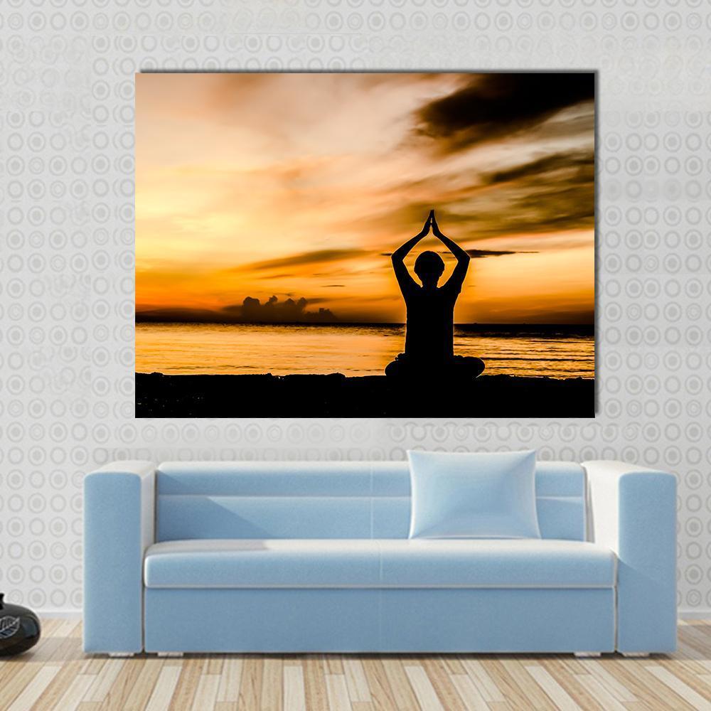 Seated Yoga Silhouette at Beach Sunset Canvas Wall Art in black, orange and yellow, single panel hung on a wall