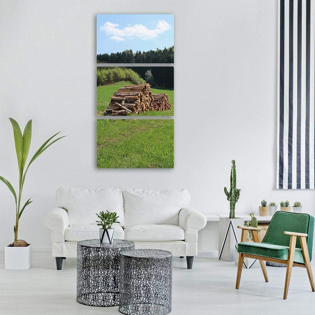 Stack of Cut Logs in Spring Meadow Vertical Canvas Wall Art in brown, green and blue, hung on a wall