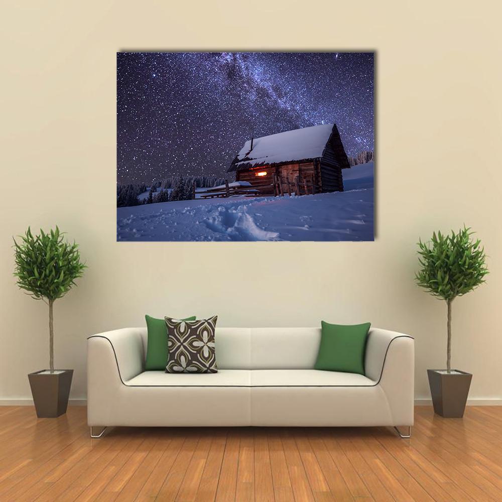 Log Cabin Under Starry Winter Sky Canvas Wall Art in white, blue and purple, single panel hung on a wall
