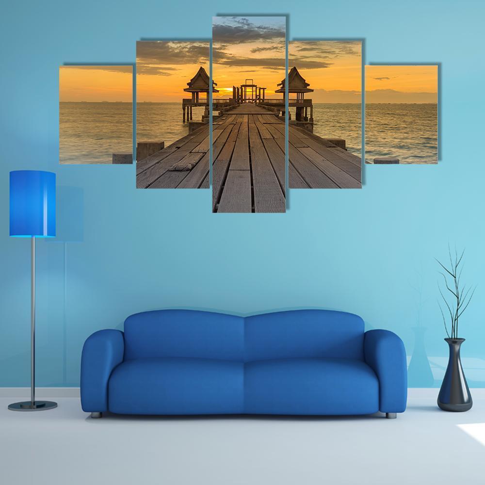 Wooden Pier to Coastal Skyline at Sunset Canvas Wall Art in gray, orange and blue, 5 panel Star layout hung on a wall