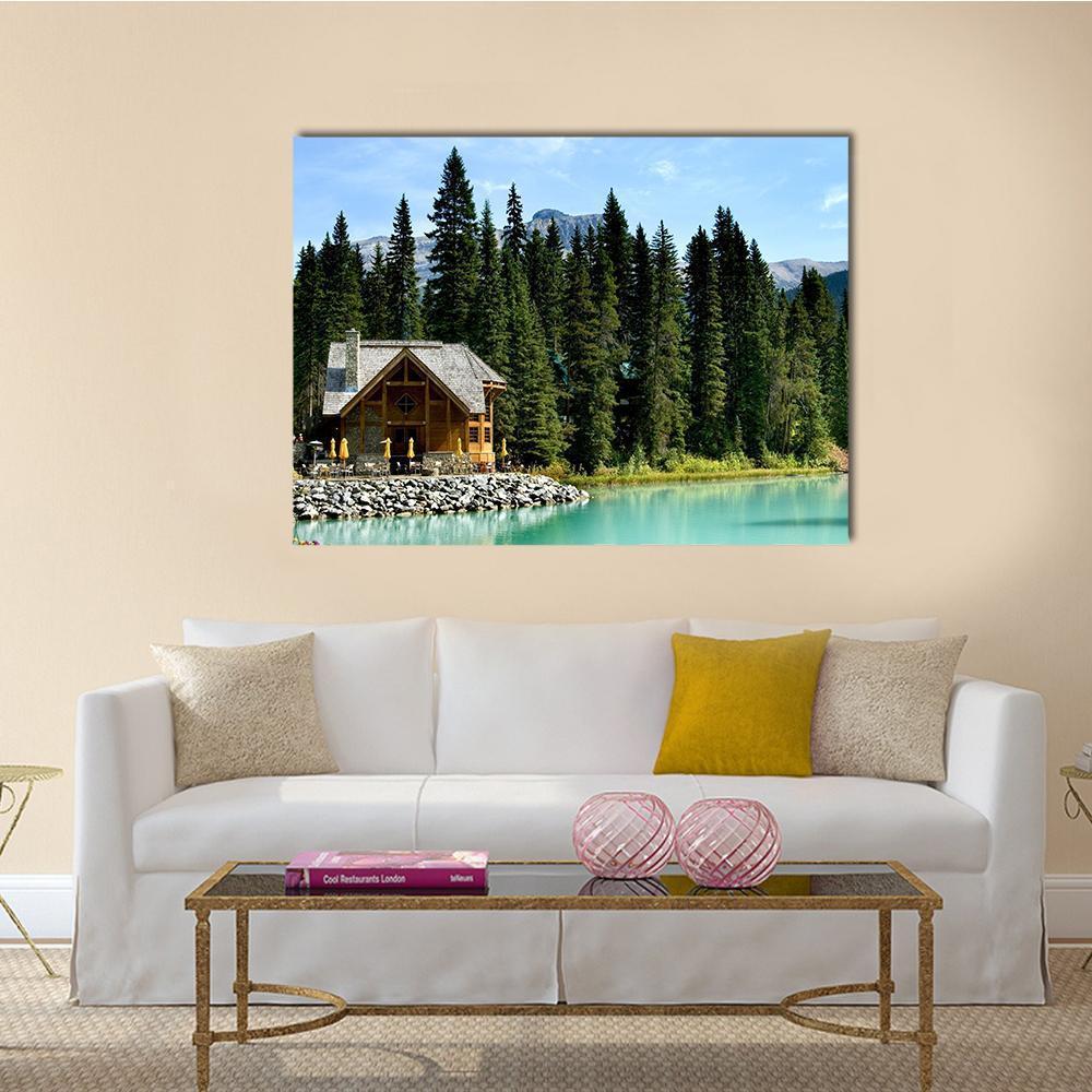 Wooden Retreat on Emerald Lake Canvas Wall Art in brown, green and blue, single panel hung on a wall