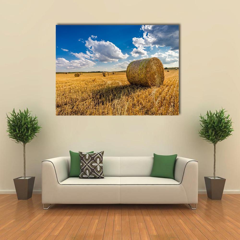 Yellow Hay Bale in a Summer Field Canvas Wall Art in gold, yellow and blue, single panel hung on a wall