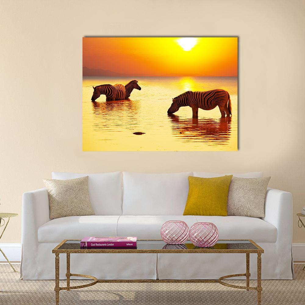 Two Zebras at Golden Sunset Canvas Wall Art in gold, orange and yellow, single panel hung on a wall